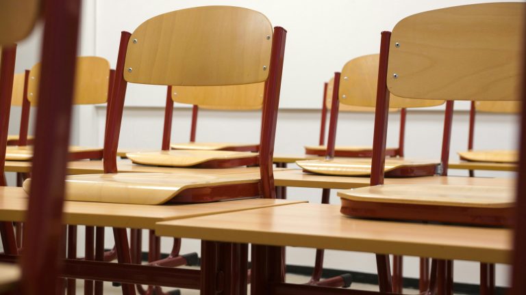 A modern and empty classroom featuring wooden chairs and desks with a focus on education and learning spaces.